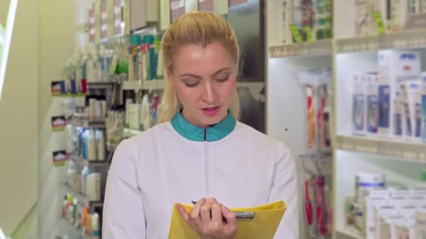 Glada kvinnliga farmaceut fylla papper, som arbetar på apotek — Stockvideo
