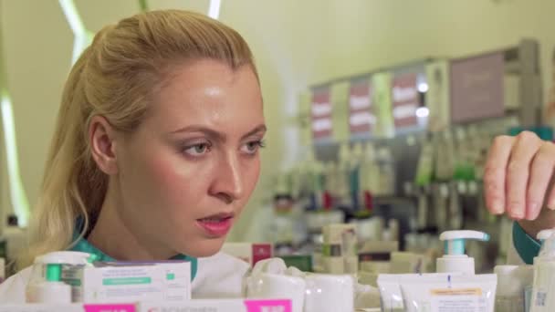 Женщина-фармацевт организует продукты на полке, работает в аптеке — стоковое видео
