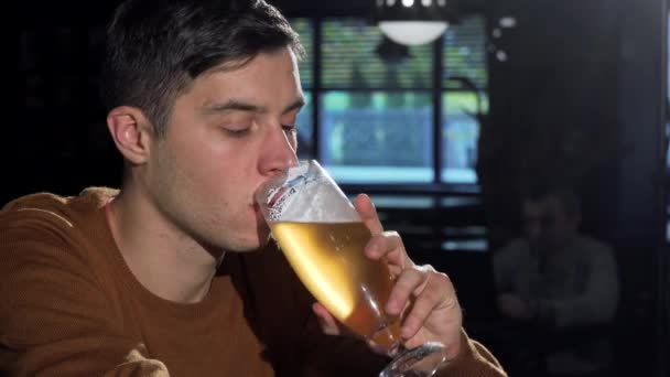 Vonzó férfi, ő üveg finom sört kortyolgatva, pihentető a bárban — Stock videók