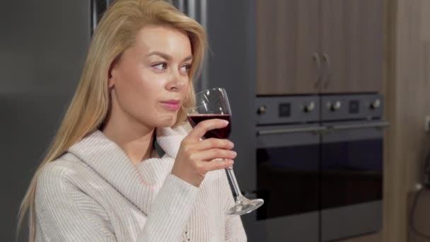 Великолепная женщина наслаждается питьем красного вина дома на кухне — стоковое видео