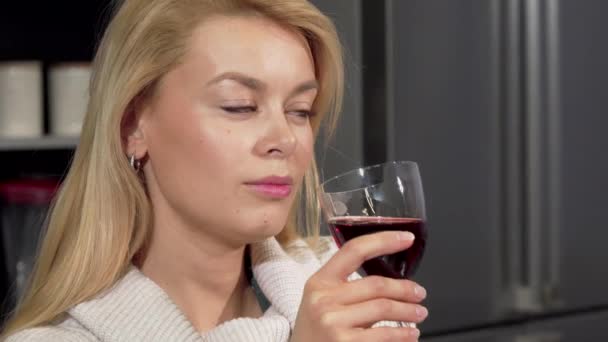 Счастливая красивая женщина улыбается камере, наслаждаясь питием вина дома — стоковое видео