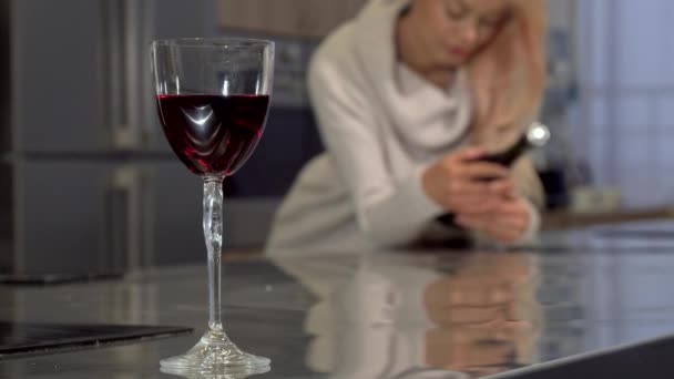 Červené víno ve sklenici na stole, Žena držící láhev na pozadí — Stock video