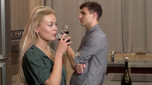 Πανέμορφη γυναίκα που πίνει κρασί στο σπίτι, ο φίλος της κοιτάζοντας της seductively — Αρχείο Βίντεο