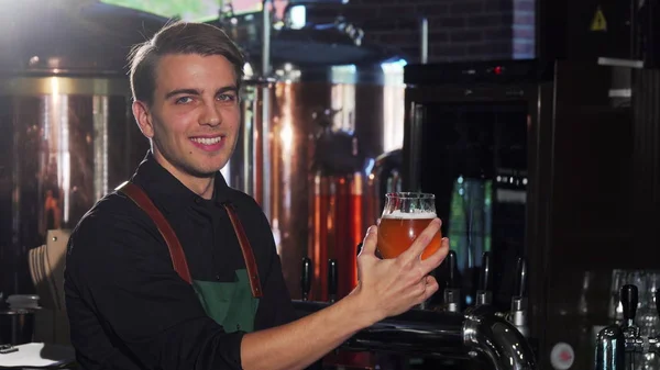 Neşeli barmen bira cam bakarak onun zanaat bira barda çalışıyor — Stok fotoğraf