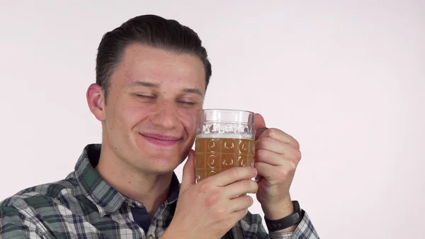 Счастливый молодой человек улыбается с закрытыми глазами, обнимается с кружкой вкусного пива — стоковое фото