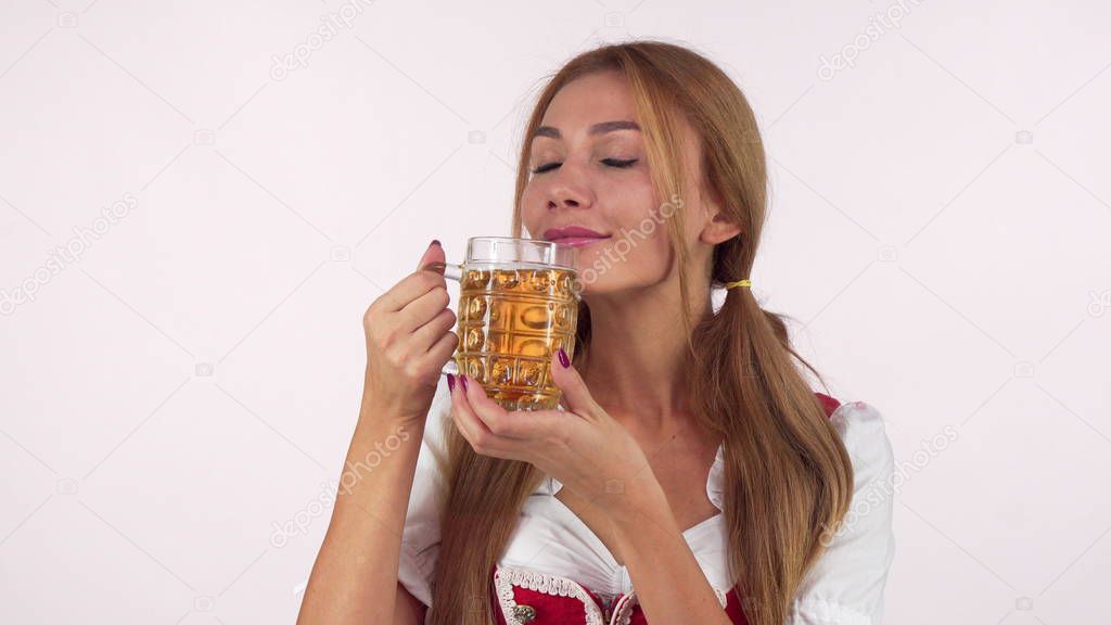 Gorgeous happy Bavarian woman enjoying smelling delicious beer