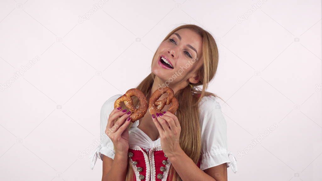 Gorgeous sexy german woman in Oktoberfest dress looking excited holding pretzels