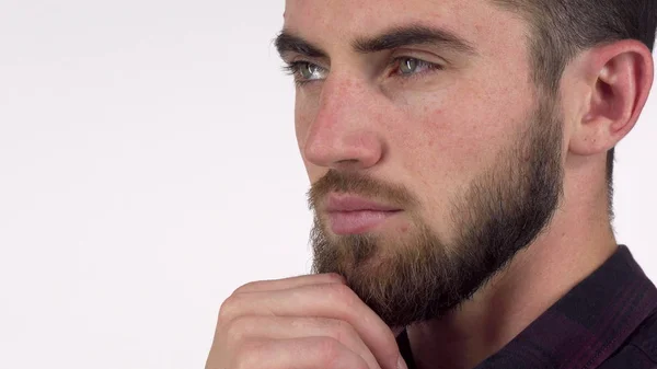 Guapo hombre serio mirando hacia otro lado pensativamente, frotándose la barba — Foto de Stock