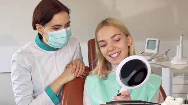 Dentista profesional y su paciente sonriendo a la cámara — Foto de Stock