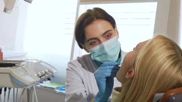 Dentista femenina trabajando, examinando los dientes de una paciente en la clínica — Foto de Stock