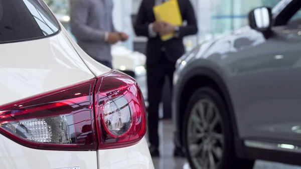Selektiver Fokus auf ein Auto, Verkäufer im Gespräch mit dem Kunden im Hintergrund — Stockfoto