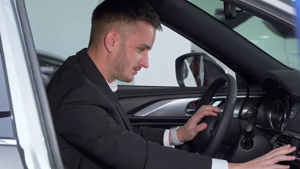 Affärsman som sitter i en ny bil, kolla insidan av ett fordon — Stockfoto