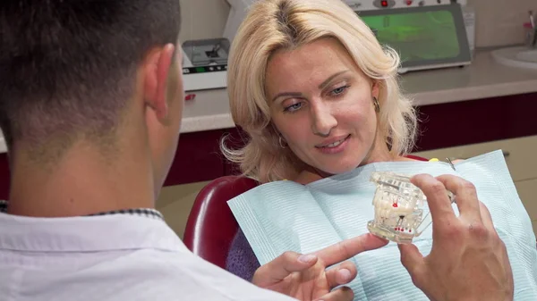 Attractive mature woman talking to the dentist at his office — Stock Photo, Image
