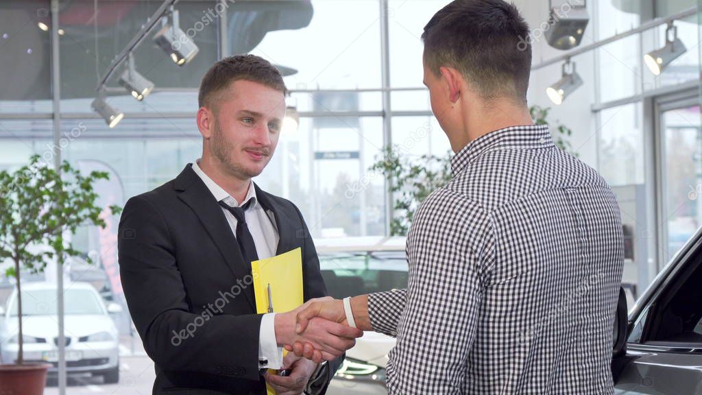 Car salesman giving car keys to the customer after shaking hands