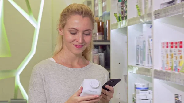 Žena pomocí chytrého telefonu, procházení informací online při nákupu léků — Stock fotografie
