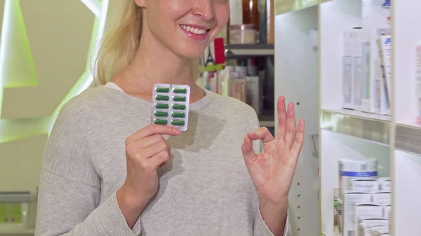 Sonriente cliente femenino mostrando signo de ok, sosteniendo píldoras ampolla en la farmacia — Foto de Stock