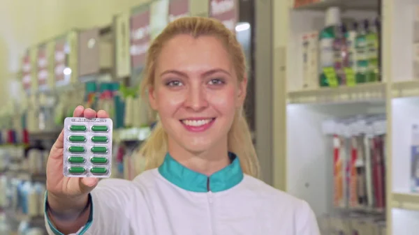 Krásné ženské lékárník napřáhl puchýř prášků do fotoaparátu — Stock fotografie