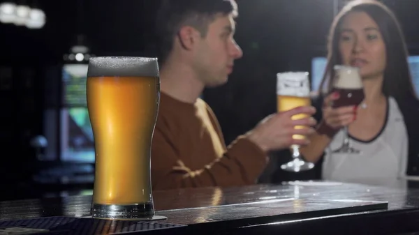 Verre de bière savoureuse au premier plan, quelques bières clinquantes sur le dos au pub — Photo