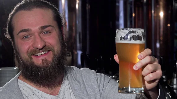 Barbu heureux homme souriant, tenant son verre de bière à la caméra — Photo