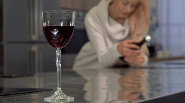 Czerwone wino w szklance na stole, Kobieta trzyma butelkę na tle — Zdjęcie stockowe