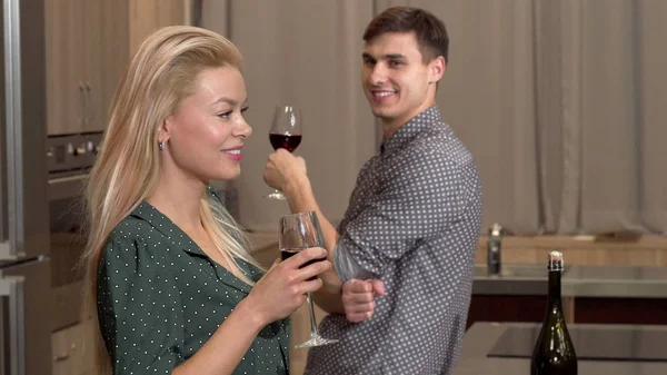 Чудова жінка п'є вино вдома, її хлопець дивиться на неї спокусливо — стокове фото