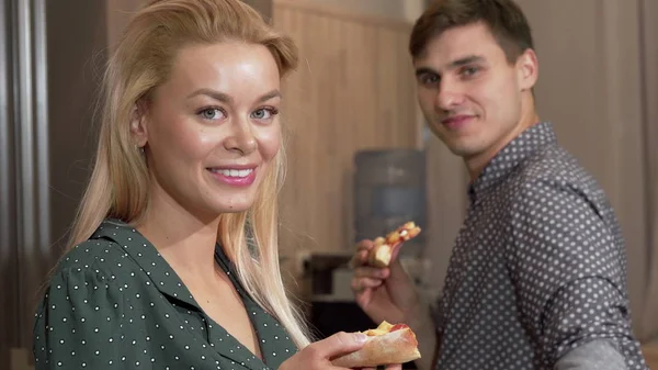 Impresionante mujer comiendo deliciosa pizza, sonriendo a la cámara con su novio —  Fotos de Stock