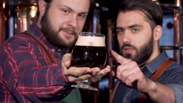 Selectieve aandacht op een glas donker bier in handen van een brouwer — Stockvideo