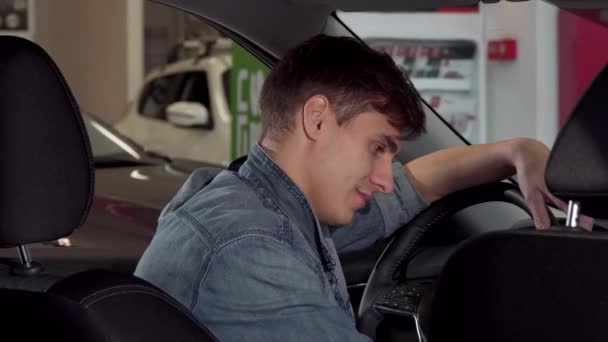 快乐英俊的男人竖起大拇指, 坐在一辆新车在经销店 — 图库视频影像