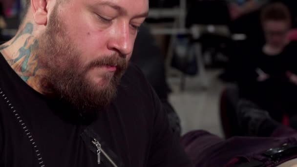 Tiro deslizante de um tatuador profissional que trabalha em sua loja de tatuagem — Vídeo de Stock