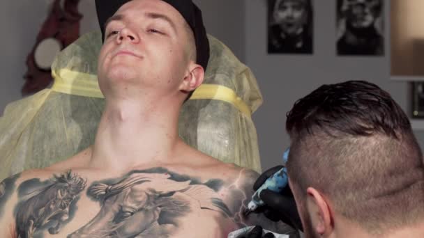 Colpo scorrevole di un bel giovane uomo che si fa tatuare il braccio — Video Stock