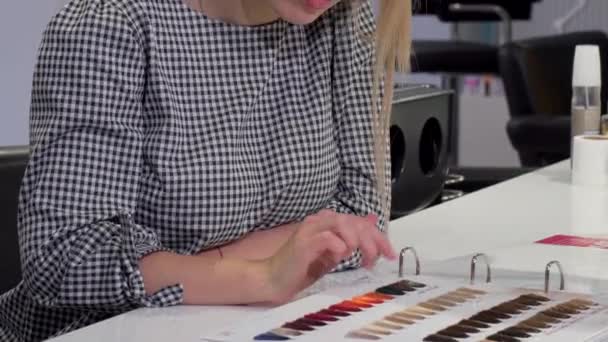 Mujer eligiendo el color de pelo del gráfico de tinte en el salón de peluquería — Vídeos de Stock