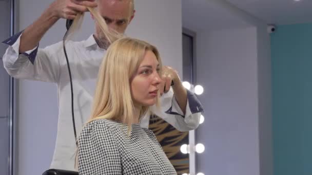 Schöne junge Frau lächelt, während sie sich die Haare vom Friseur frisieren lässt — Stockvideo