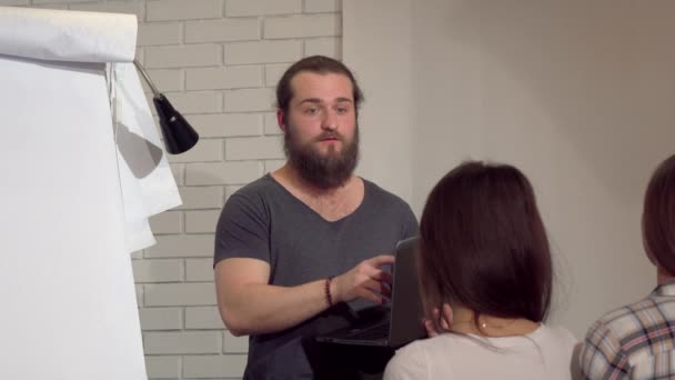 Молодой бородатый бизнесмен ведет встречу с коллегами в офисе — стоковое видео