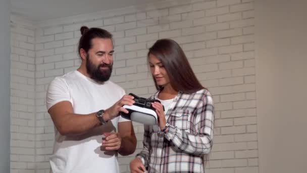 英俊的胡须男子看着他的女朋友使用虚拟现实眼镜 — 图库视频影像