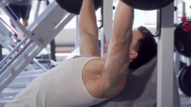 Yakışıklı kaslı adam spor salonunda tezgah basın yapıyor