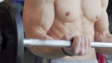 Tanınmaz kas gömleksiz adam bir halter ile pazı bukleler yapıyor