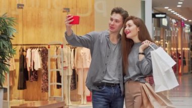 Alışveriş merkezinde alışveriş yaparken selfie çeken sevimli genç çift