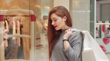 Alışveriş merkezinde alışveriş keyfi, ekranda giysi inceleyerek çekici kadın