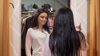 Giyim mağazasında bir ayna önünde giysi çalışıyor Charming genç kadın