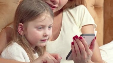 Annesi ile akıllı telefon kullanarak sevimli küçük kız