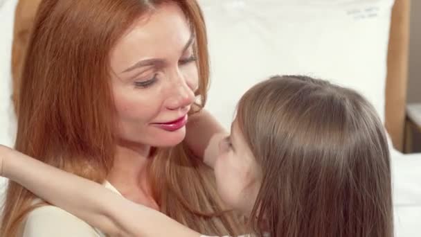 Gelukkige moeder knuffelen haar kleine dochter knuffelen, glimlachend naar de camera — Stockvideo