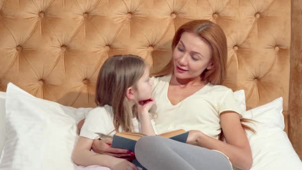 Atractiva mujer disfrutando leyendo un libro con su adorable hijita — Vídeos de Stock
