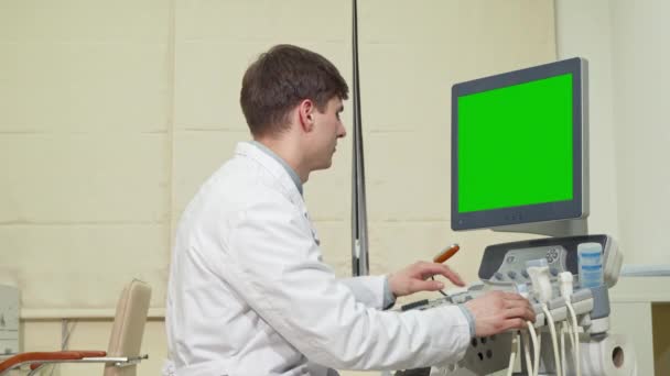 Médico varón joven usando escáner de ultrasonido con pantalla verde — Vídeos de Stock