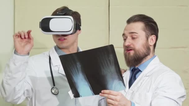 Médico varón con anteojos vr, su colega examinando la radiografía de un paciente — Vídeo de stock