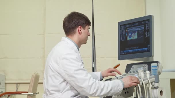 Bonito médico alegre sorrindo para a câmera, segurando scanner de ultra-som — Vídeo de Stock