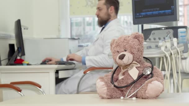 Pediatra maschio esaminando la risonanza magnetica, peluche orsacchiotto giocattolo in primo piano — Video Stock