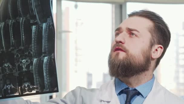 Bearded male doctor examining mri scan of his patient — Stock Video