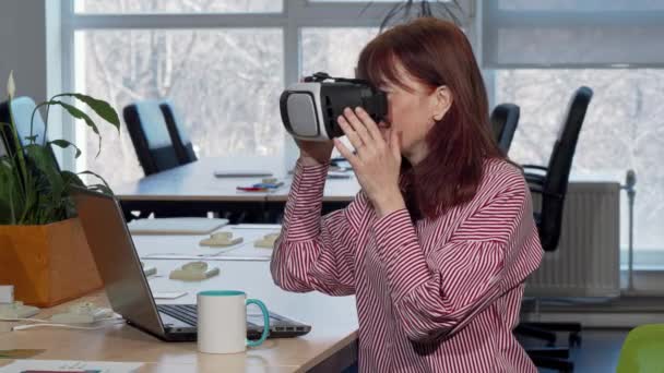 Madura mujer de negocios disfrutando de usar auriculares de realidad virtual en su lugar de trabajo — Vídeos de Stock