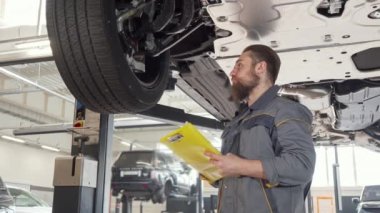 Bir sakallı araba tamircisi notlar alarak düşük açı çekim, kaldırdı otomatik inceleyerek