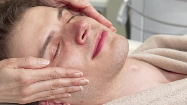 Снимок счастливого человека, наслаждающегося массажем головы и лица в спа-центре — стоковое видео